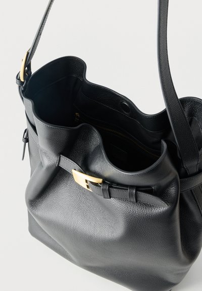 Μαύρη τσάντα ώμου από δερματίνη με χρυσή πόρπη, ανοιχτό πάνω μέρος που αποκαλύπτει εσωτερική τσέπη με φερμουάρ και δομημένες εσωτερικές θήκες.