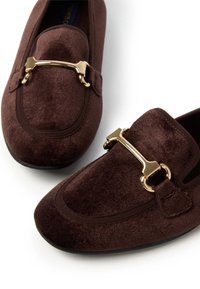 Braune Samt-Loafers mit einer goldfarbenen Hardware-Akzent, runder Zehenform und dezenten Steppdetails auf dem Obermaterial und an den Seiten.