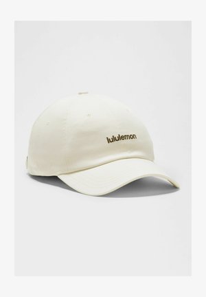 Gebroken-witte honkbalpet met gebogen klep, met een klein "lululemon"-logo geborduurd in het bruin op het voorpaneel.