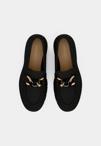 Mustad kergete materjalidega libistatavad kingad, millel on kuldse ja musta keti aksent, polsterdatud sisetald ja tekstuuriga tald.