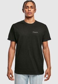 Zwarte katoenen t-shirt met korte mouwen en een ronde hals, met een witte tekst "Just Love" en een hartgrafiek op de borst.