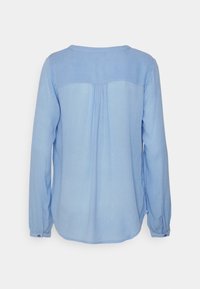 Blusa a maniche lunghe blu chiaro con scollatura rotonda, dettagli plissettati sul retro e polsini con bottone. Realizzata in un tessuto morbido e leggero.