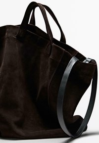 Brun ruskind tote taske med to korte håndtag. Har en sort læderrem for ekstra støtte. Blød tekstur, dyb farve og solid konstruktion.