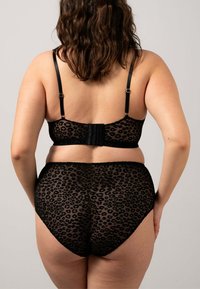 Schwarzer Spitzen-Bralette und hochgeschnittene Pantys mit Leopardenmuster. Verstellbare Träger und ein Haken- und Ösenverschluss auf der Rückseite.