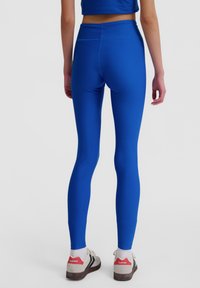 Blå, högmidjade leggings gjorda av stretchigt tyg, med en slät textur och en skräddarsydd passform som följer kroppens konturer.