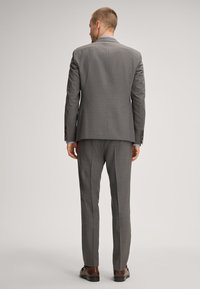 Gray suit with a tailored design, featuring a two-button closure, notch lapels, and slim fit trousers. Completed with brown shoes.