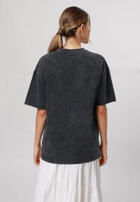 Black oversized t-shirt in washed cotton. Crew neckline, short sleeves, and a soft texture. Visible stitching and a relaxed fit.