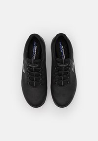 Zapatillas deportivas negras con punta redonda, parte superior texturizada, cierre con cordones, plantilla acolchada y la marca "Skechers Memory Foam" visible en el interior.