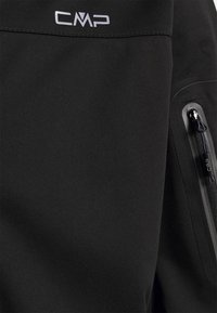 Zwarte softshell jas met een ritszak, CMP-logo aan de bovenkant, een soepele textuur en een minimalistisch ontwerp.
