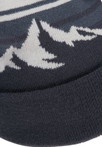Strickmütze in dunkelblau mit weißem Bergmotiv. Verfügt über einen strukturierten Rand und einen weichen, flexiblen Stoff für optimalen Komfort.