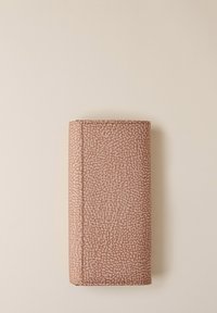 Portafoglio rettangolare piegato con un motivo testurizzato di piccoli punti irregolari color pesca e crema su uno sfondo beige.