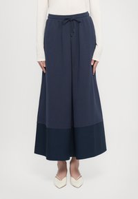 Marineblaue Culottes mit einem Kordelzugbund, aus weichem Stoff gefertigt. Besitzen ein Farbkombinationsdesign mit einem dunkleren marineblauen Akzent am Saum.