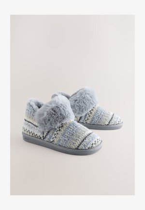 Gestrickte blaue und gelbe Hausschuhe mit Muster, grauem Kunstpelzbesatz und grauen Gummisohlen. Weiche Textur mit gemütlichem Design.