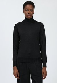 Schwarzer Rollkragenpullover mit geripptem Hals- und Armsaum, der eine glatte Textur und eine taillierte Passform aufweist, kombiniert mit lockeren schwarzen Hosen.