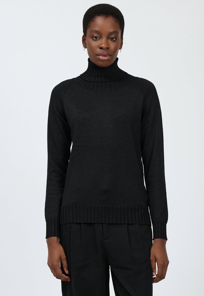 Schwarzer Rollkragenpullover mit geripptem Hals- und Armsaum, der eine glatte Textur und eine taillierte Passform aufweist, kombiniert mit lockeren schwarzen Hosen.