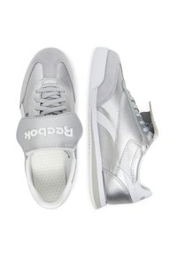 Un paio di sneakers Reebok argento e bianche con lacci e una fascia larga su una scarpa, mostrato da viste superiori e laterali.