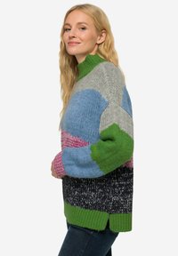Kleurvolle gebreide trui met een hoge groene kraag, voorzien van grote blokken met patronen in blauw, roze, grijs en zwart, losse pasvorm, zachte textuur.
