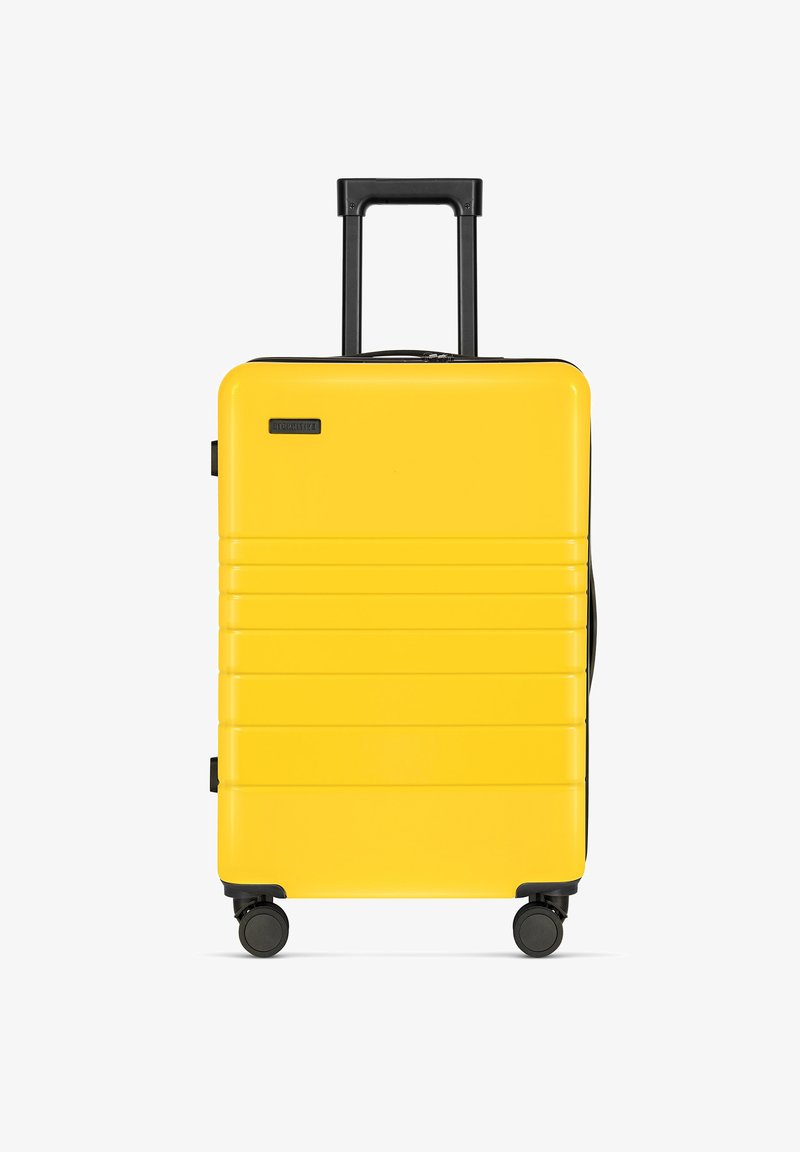 Gelber Hartschalenkoffer mit Rillen, schwarzem ausziehbarem Griff und vier schwarzen Rädern. Kompaktes, leichtes Design für den Reisegebrauch.