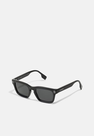 Óculos de sol pretos com armação retangular, acabamento mate, lentes escuras e três riscas horizontais em cada haste. Design minimalista.