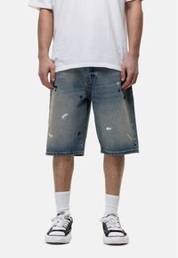 Leren denim shorts in lichtblauw met een vervaagde wassing, voorzien van versleten details en een rechte snit. Draag ze met een wit t-shirt en zwarte sneakers.