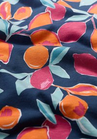 Cotton fabric featuring a floral pattern with orange, pink, and teal leaves on a dark navy background. Textured appearance with creases.