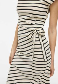 Sukienka w paseczki z czarno-kremowymi poziomymi paskami, krótkimi rękawami, dopasowanym gorsetem oraz detalem w postaci kokardy po boku w talii.