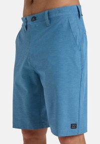 Blauwe shorts van textuurstof, met een knoopsluiting, zijzakken en een klein logopatch op de linkerpunt.