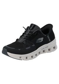Chaussures de sport noires et grises avec une tige en maille, des détails texturés, une semelle légère et des accents de rembourrage blanc bien visibles. Comprend des lacets.