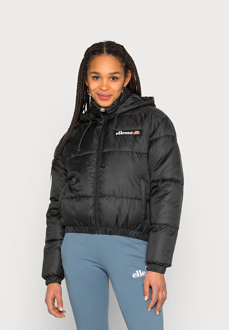 Svart boblejacket med cropped design, elastiske mansjetter, frontglidelås og hette. Har brodert merkelogo på brystet.