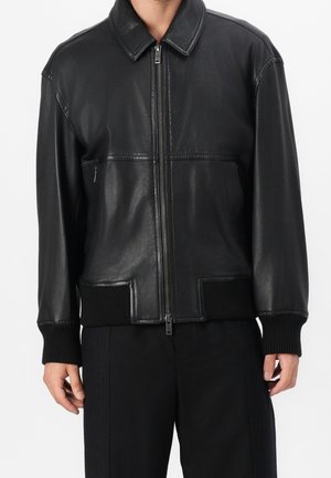 Zwarte leren bomberjack met een ritssluiting aan de voorkant, geribbelde boorden en zoom. Heeft een gladde textuur en twee voorzakken, met minimale stiknaden.