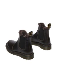 Stivali ankle in pelle marrone con sottoscarpa in pelliccia sintetica, pannelli laterali elastici e cuciture gialle su una suola spessa. Presenta linguette per una vestibilità facile.