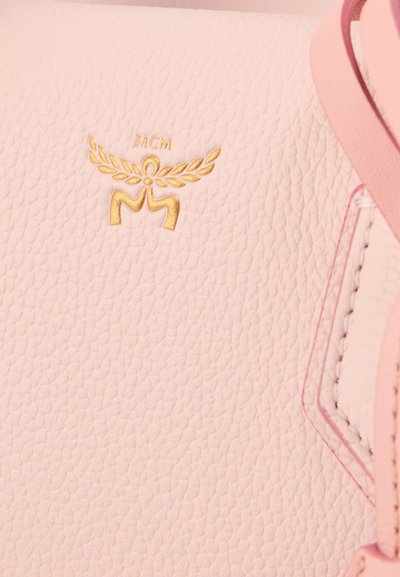 Τσάντα χειρός από δέρμα σε απαλό ροζ χρώμα με υφή, διακοσμημένη με ανάγλυφο χρυσό λογότυπο και ταιριαστά ροζ στοιχεία. Περιλαμβάνει λεπτομερή ραφή.