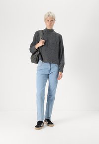 Grey ribbed knit sweater, light blue straight-leg jeans, black sneakers with white accents, and a dark shoulder bag.