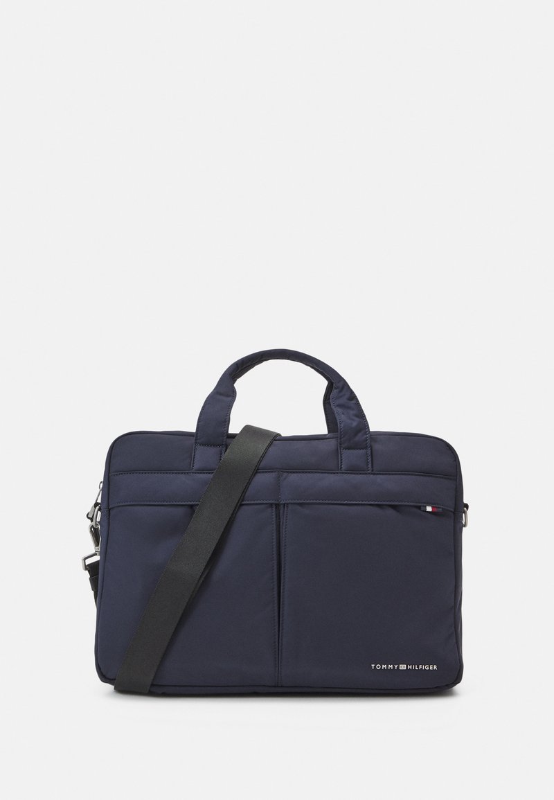 Navy nylon laptop bag with two short handles and a detachable shoulder strap. Features front zip pocket and subtle logo detail.