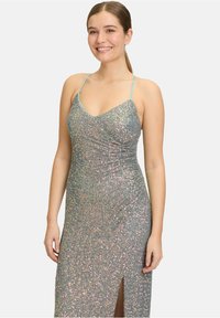 Funkelndes langes Kleid mit taillierter Passform, hergestellt aus schimmerndem Material. Hat dünne Träger, einen V-Ausschnitt und einen seitlichen Schlitz bis zum Oberschenkel.
