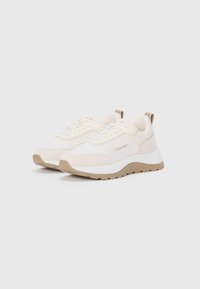 Sneaker bianchi con accenti beige, dotati di una parte superiore testurizzata, chiusura con lacci, collo imbottito e una suola in gomma spessa e con motivo.