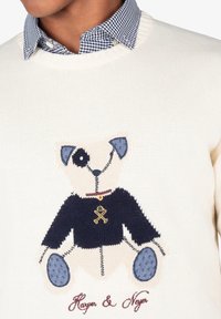Suéter blanco de punto con un oso de peluche bordado en azul marino y celeste, con un detalle de cuello en cuadros. Debajo, aparece bordado "Harper & Neyer".