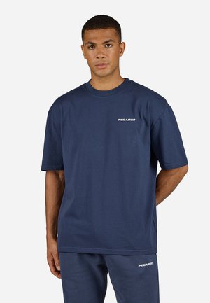 Tricou din bumbac de culoare bleumarin, cu mâneci scurte, guler rotund și logo alb "PEGADOR" pe pieptul stâng. Textură netedă și croială lejeră.