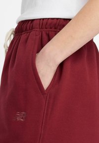 Bordeauxrood sweatpants gemaakt van zachte stof met een elastische tailleband en een trekkoord, voorzien van zijzakken en een subtiel logodetail.