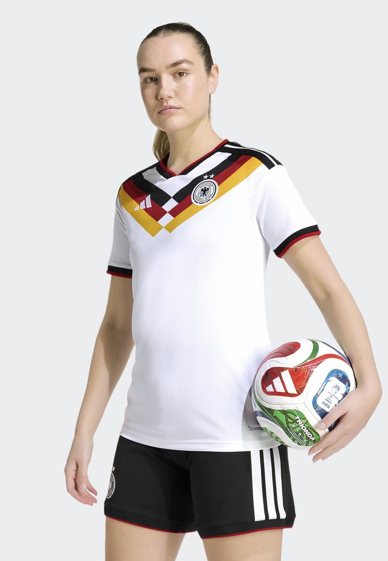 Germany national team soccer jersey in white with a colorful diagonal design, black shorts, and a multicolored soccer ball with patterns.