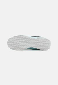 Suola di sneaker azzurro chiaro con un motivo a spina di pesce, caratterizzata da una base in gomma bianca e un accento blu scuro nella parte superiore.
