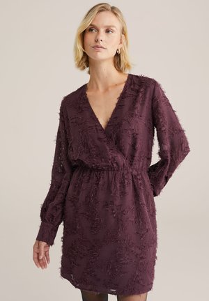 Rochie bordeaux cu decolteu adânc în V, mâneci lungi și material texturat cu un model shaggy. Talie elastică pentru un design ajustat.