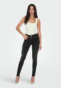 Jeans ajustados negros de cintura alta, con un diseño de cinco bolsillos, cierres de botón metálico y una textura de denim suave.
