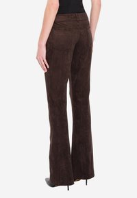 Brązowe zamszowe spodnie dzwonowate o gładkiej fakturze, z tylnymi kieszeniami i pasem. Dopasowany krój zapewniający korzystną sylwetkę.