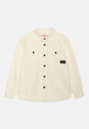 Camicia button-up di colore crema con maniche lunghe, tasche sul petto, bottoni neri e un piccolo etichetta del marchio sulla tasca sinistra.