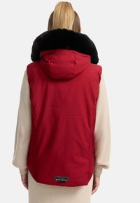 Gilet rosso imbottito con colletto in pelliccia sintetica nera, cappuccio e etichetta con logo all'orlo. Tessuto liscio con dettagli trapuntati sul retro.