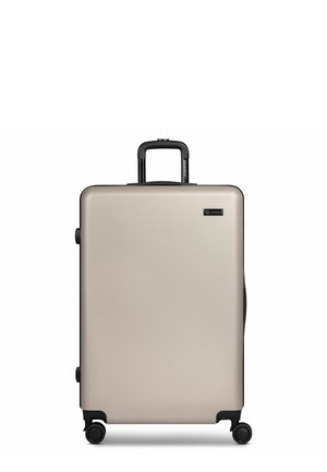 Grote beige harde koffer met vier zwarte zwenkwielen en een zwarte uitschuifbare handgreep, rechtopstaand op een witte achtergrond.