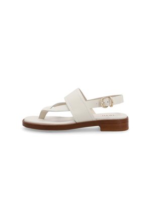 Sandalo flat in pelle bianca con suola in legno, cinturino regolabile alla caviglia e anello per le dita su sfondo bianco.