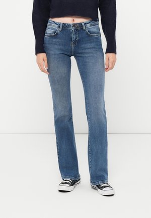 Blue denim jeans with a flared leg design, featuring five pockets, a button closure, and a faded finish. Worn with black sneakers.