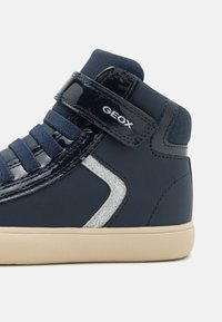 Meremeeste siledast sünteetilisest materjalist kõrge varbaga sneaker, millel on takjapael, tekstuuriga ninad ja hõbedane aksent külje peal.